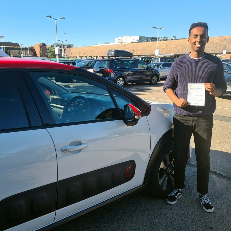 A student holding their pass certificate in front of the Hedgehog Driving Academy car
