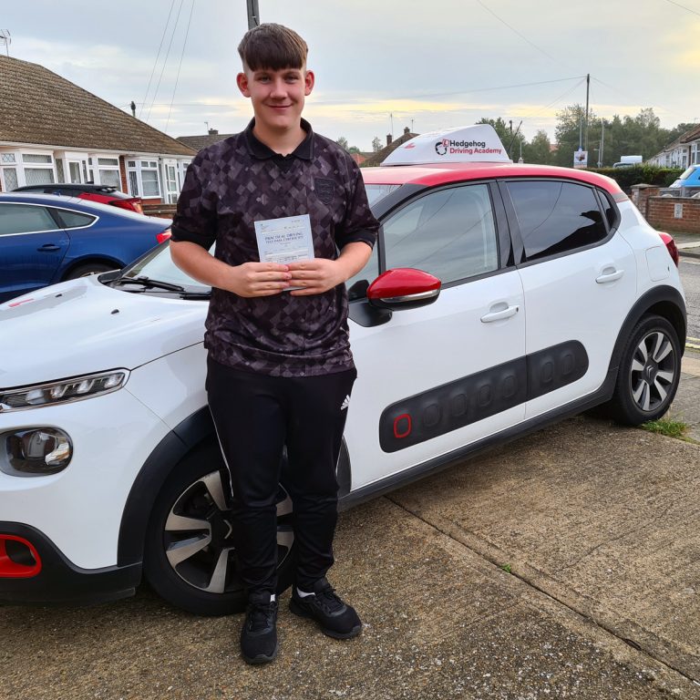 A student holding their pass certificate in front of the Hedgehog Driving Academy car