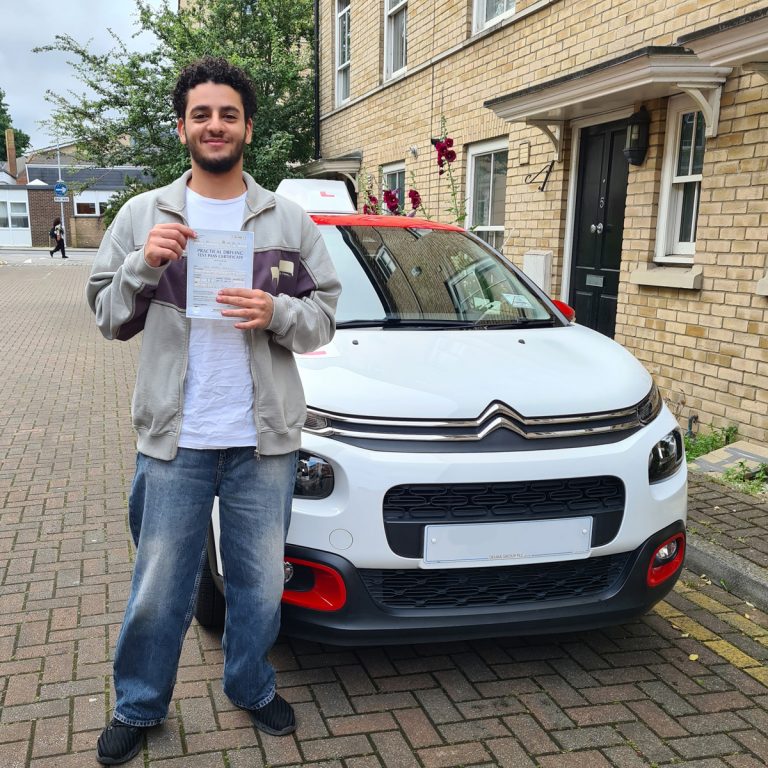 A student holding their pass certificate in front of the Hedgehog Driving Academy car