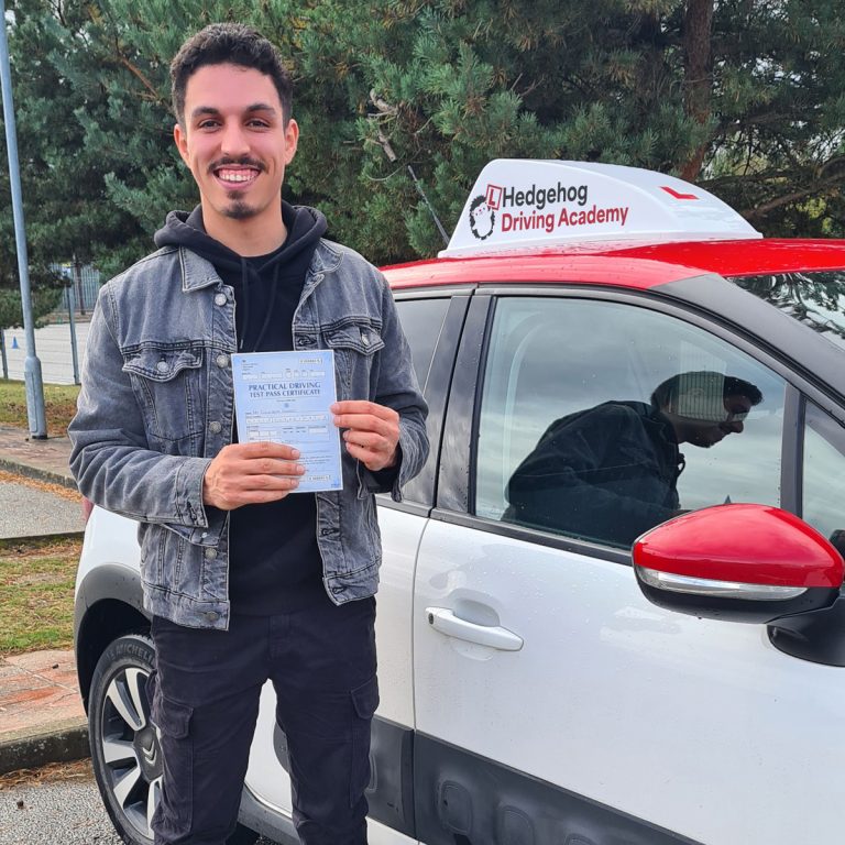 A student holding their pass certificate in front of the Hedgehog Driving Academy car