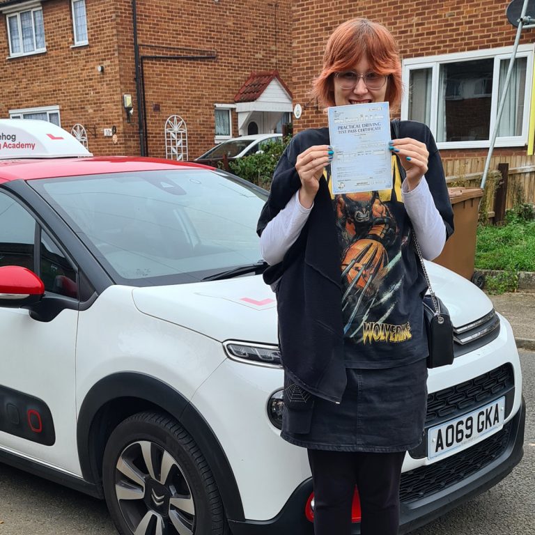 A student holding their pass certificate in front of the Hedgehog Driving Academy car