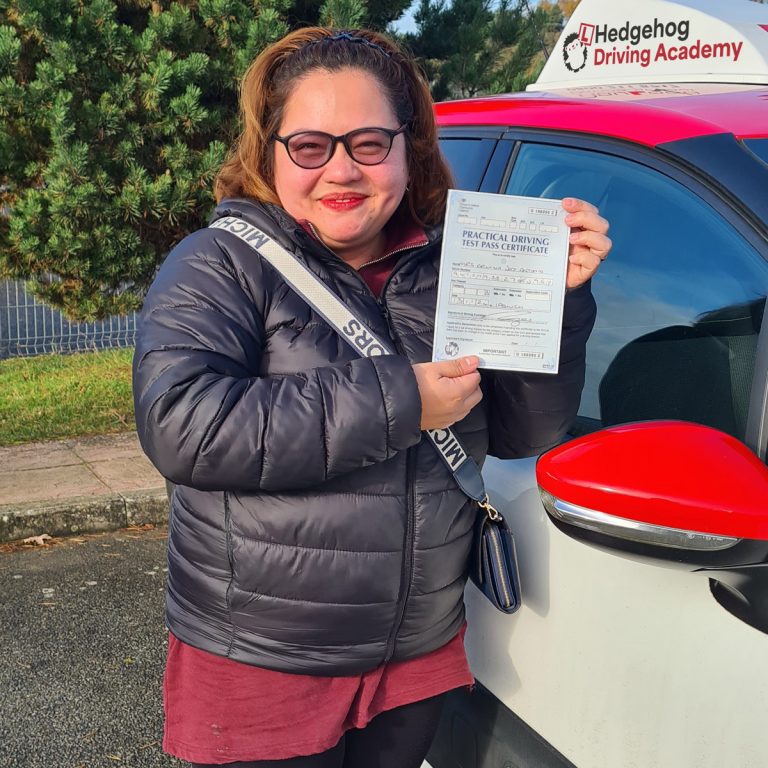 A student holding their pass certificate in front of the Hedgehog Driving Academy car