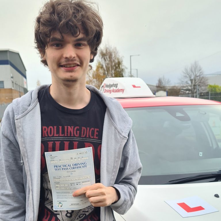 A student holding their pass certificate in front of the Hedgehog Driving Academy car