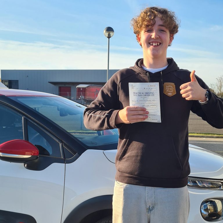 A student holding their pass certificate in front of the Hedgehog Driving Academy car